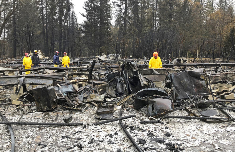 Search team members move sheet metal to allow cadaver dogs to search beneath them for signs of human remains at a mobile home park in Paradise, Calif., Friday, Nov. 23, 2018. They said the mobile home park had already been hand searched, so they were re-examining it with search dogs. (AP Photo/Kathleen Ronayne)