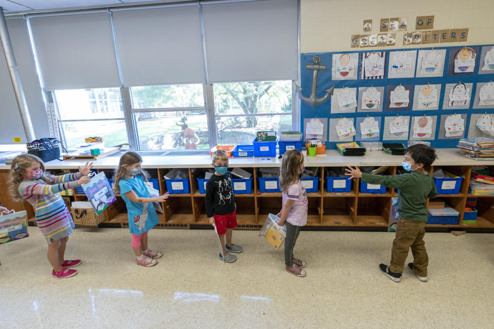 Kindergarten students check to make sure they are standing at the proper social distancing space as they line up to go outside during the coronavirus outbreak at the Osborn School, Tuesday, Oct. 6, 2020, in Rye, N.Y. (AP Photo/Mary Altaffer)
