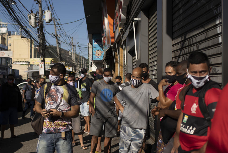 Customers wait to enter the Madureira Market in Rio de Janeiro, Brazil, Wednesday, June 17, 2020. Rio continues with its plan to ease restrictive measures and open the economy to avoid an even worse economic crisis, amid the new coronavirus pandemic. (AP Photo/Silvia Izquierdo)