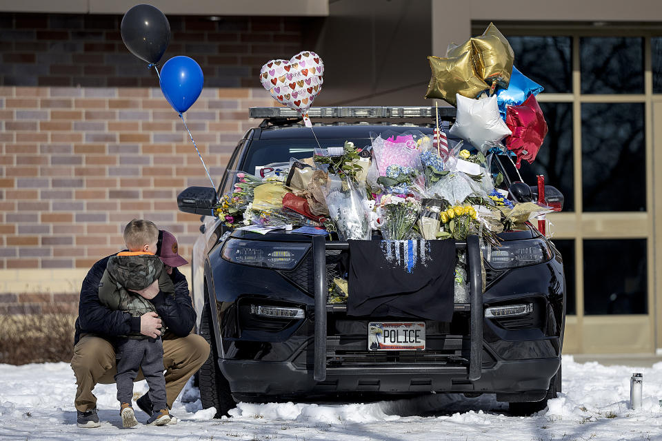 Zach Osterberg, of the Savage Fire Department, hugs his son Lincoln as they paid their respect at three memorials in front of the Burnsville Police Department in Burnsville, Minn., Monday, Feb. 19, 2024. Two police officers and a first responder were shot and killed early Sunday and a third officer was injured at a suburban Minneapolis home in an exchange of gunfire while responding to a call involving an armed man who had barricaded himself inside with family. (Elizabeth Flores/Star Tribune via AP)