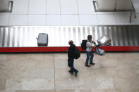 Pasajeros que acaban de aterrizar en el Aeropuerto Adolfo Suárez-Madrid Barajas (España) esperan con mascarillas a recoger sus maletas en la sala de equipaje. (Foto: Sergio Perez / Reuters).