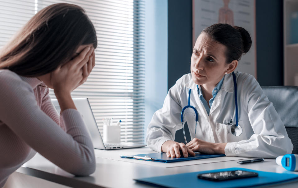 Professional doctor assisting a woman in her office: the patient is crying and feeling hopeless