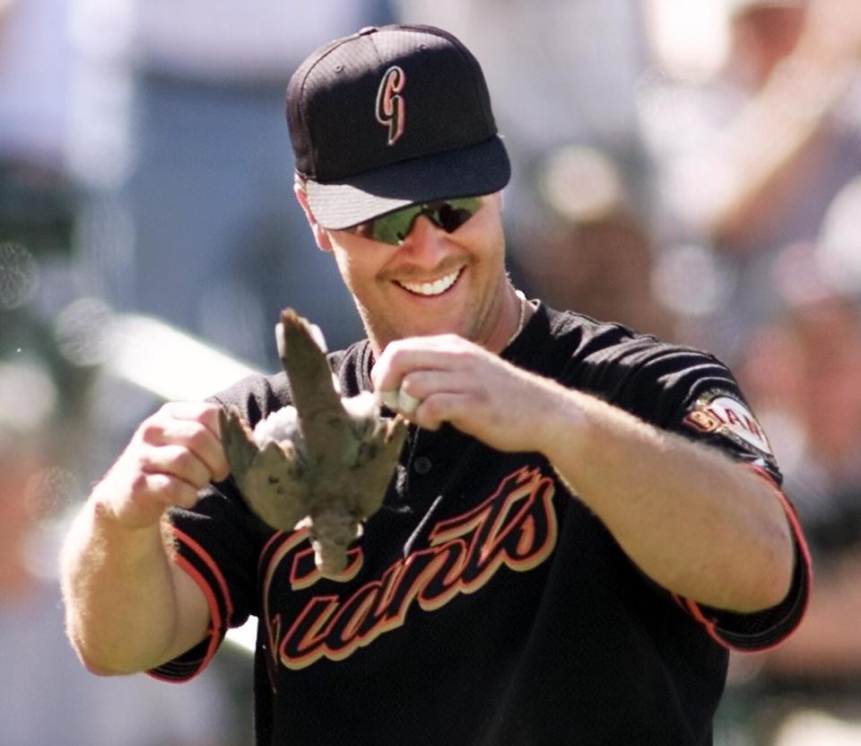 A baseball player holds a dead bird.