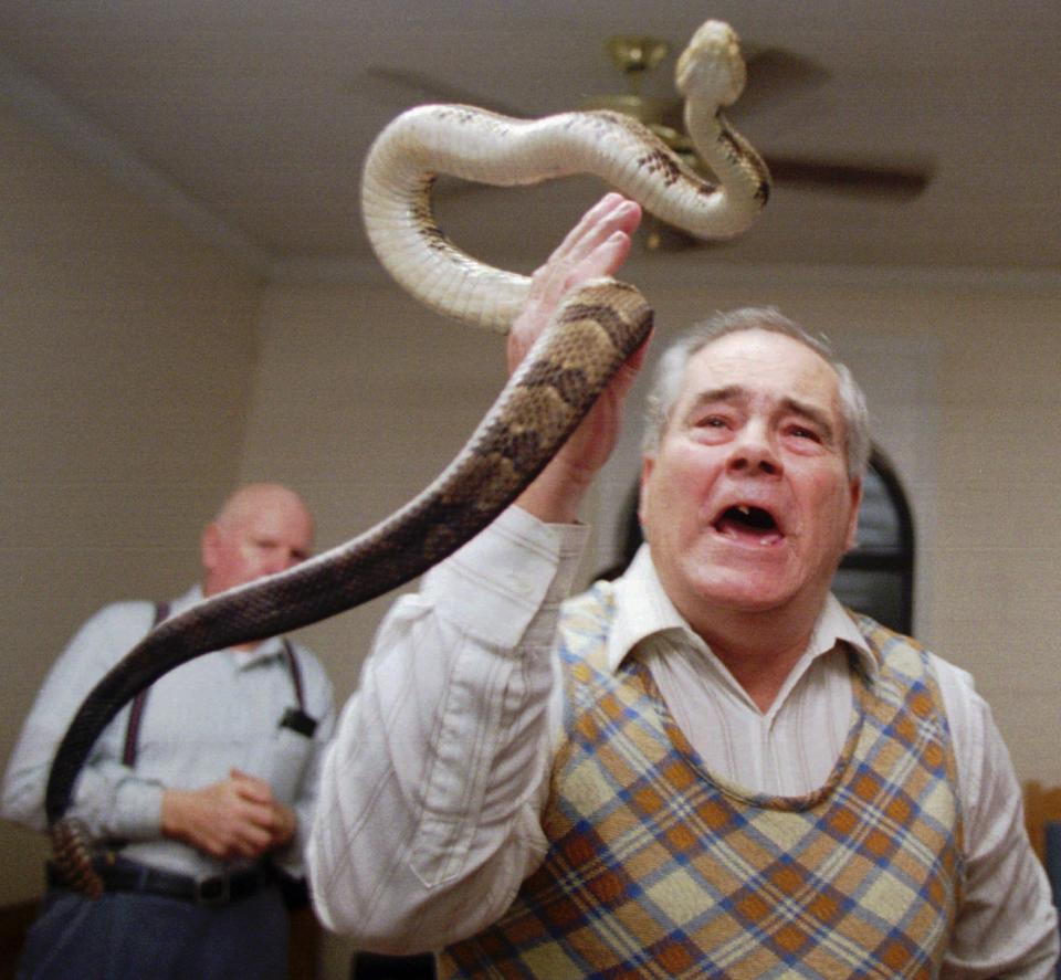 FILE - In this Feb. 25, 1995 file photo, Junior McCormick tests his faith by handling a rattlesnake as Homer Browing looks on during services at the Church of the Lord Jesus in Kingston, Ga. Church members believe that if they have faith in God, they will be protected from harm as they handle the serpents. (AP Photo/John Bazemore)