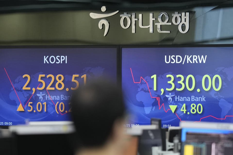 A currency trader walks by the screens showing the Korea Composite Stock Price Index (KOSPI), left, and the foreign exchange rate between U.S. dollar and South Korean won at a foreign exchange dealing room in Seoul, South Korea, Tuesday, April 25, 2023. Asian stocks were mixed Tuesday after Wall Street edged higher as investors awaited U.S. earnings reports and an update on economic growth.(AP Photo/Lee Jin-man)