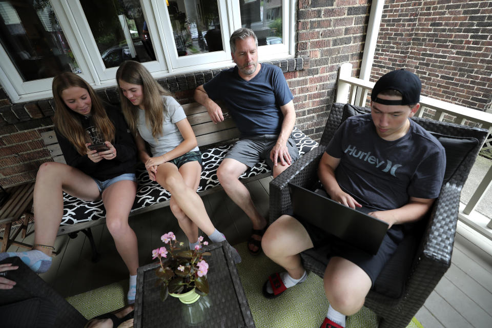 From left, twins Ruby and Lola, their father, David Wood, and their brother, Ethan, sit together on their porch in Toronto, Canada, on Monday, July 12, 2021. When Canada recently began immunizing children from 12 years of age, Amanda Wood, who manages child actors, and her architect husband didn't hesitate to get the kids vaccinated. (AP Photo/Kamran Jebreili)