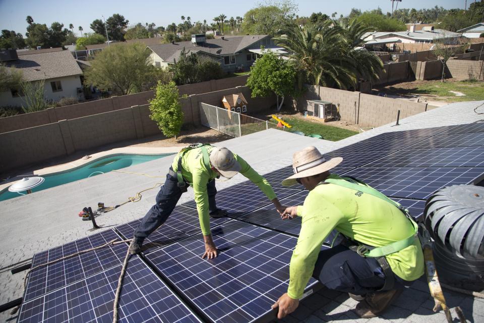 Workers install solar panels on a residential roof in 2017.