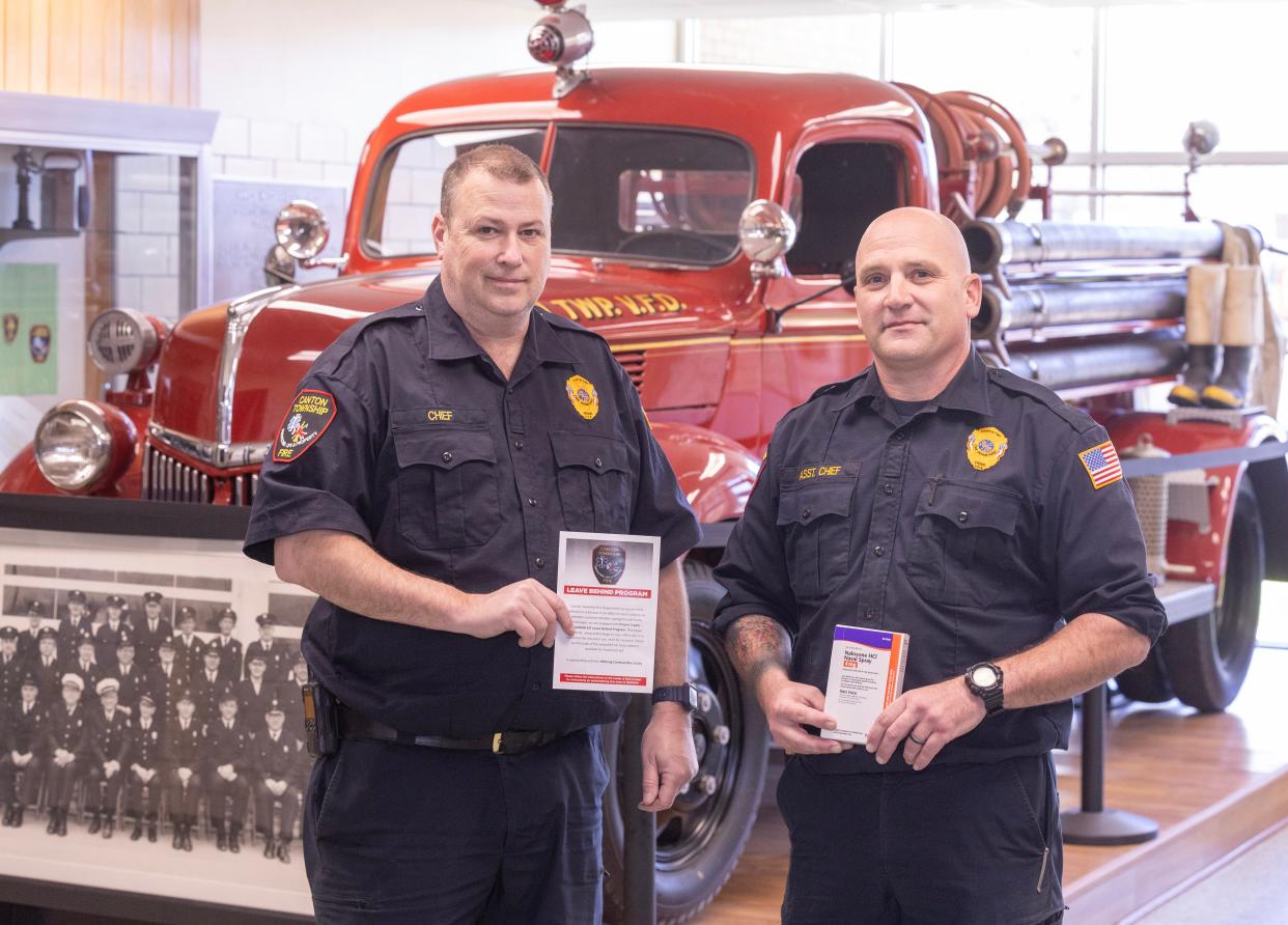 Canton Township Fire Chief Chris Smith, left, and Assistant Chief Rick Morabito hold a pamphlet and a box of naloxone that firefighters give to overdose survivors. The pamphlet has information about using naloxone to treat opioid overdoses and a list of local mental health and addiction recovery services.