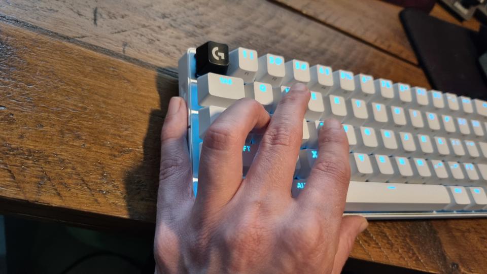 Ένα χέρι σαν νύχι που σχηματίζει σχήμα σαν νύχι στο Logitech Pro X60 για χρήση του τροχού έντασης