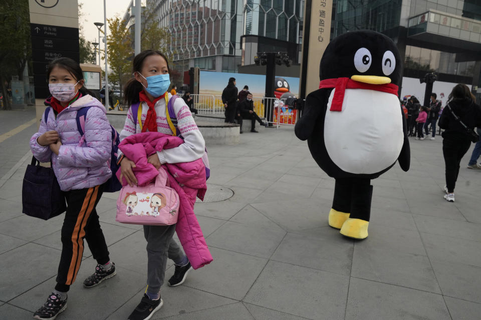 Children past by a mascot for Tencent during a promotion event in Beijing on Wednesday, Nov. 11, 2020. China is banning children from playing online games for more than three hours a week, the harshest restriction so far on the game industry as Chinese regulators continue cracking down on the technology sector. (AP Photo/Ng Han Guan)