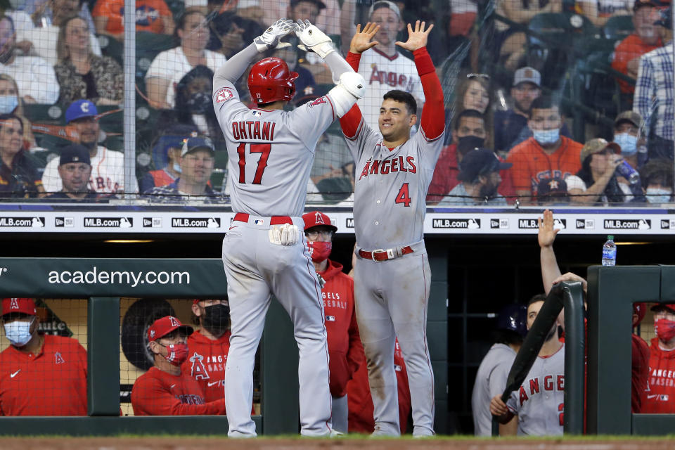 Los Angeles Angels designated hitter Shohei Ohtani (17) and Jose Iglesias (4) high five at the dugout after Ohtani's home run during the eighth inning of a baseball game against the Houston Astros Sunday, April 25, 2021, in Houston. (AP Photo/Michael Wyke)