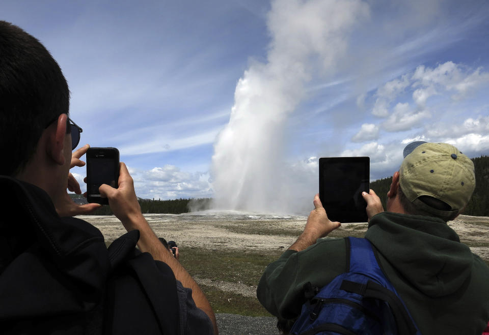People use phones and tablets to photograph Old Faithful geyser erupting in Yellowstone National Park. The geyser's&nbsp;steam can top 300-degrees. (Photo: Jim Urquhart / Reuters)