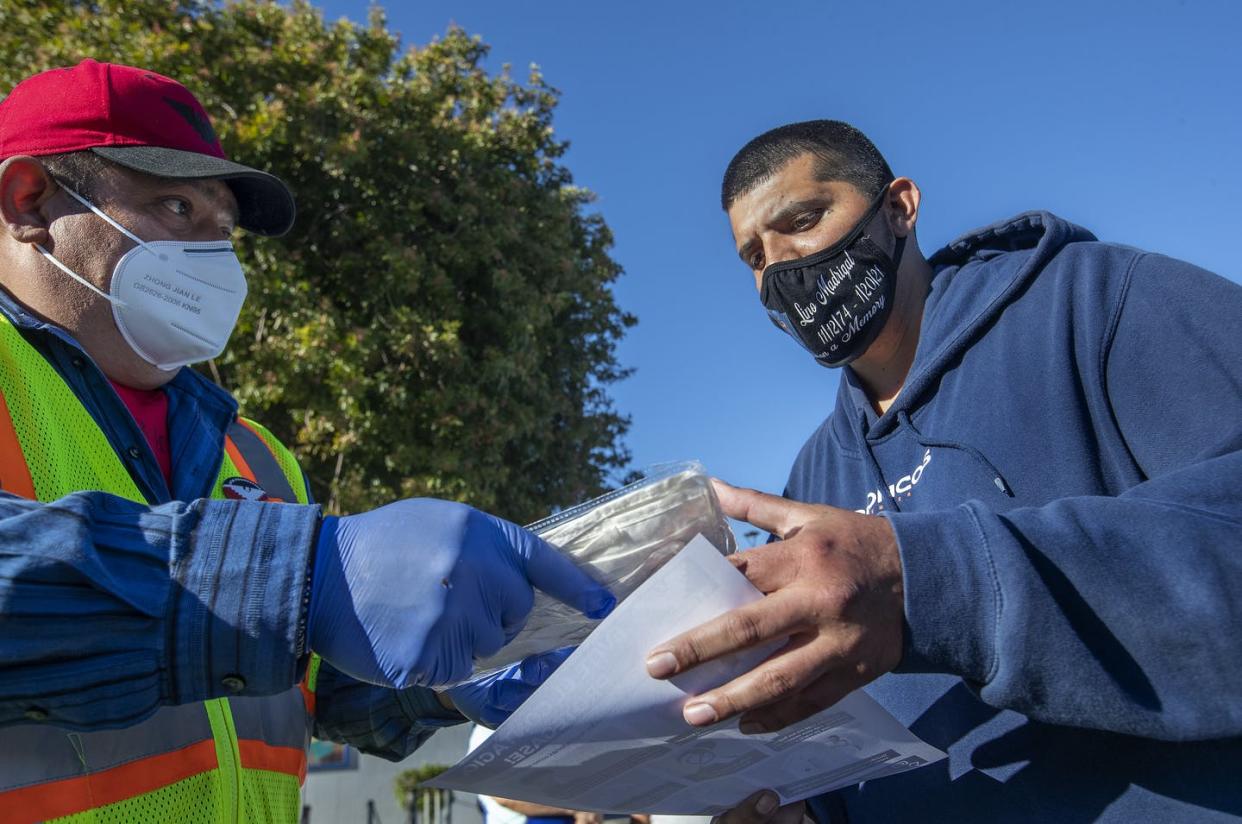 <span class="caption">A volunteer distributes face masks in a rural California community in February 2021.</span> <span class="attribution"><a class="link " href="https://www.gettyimages.com/detail/news-photo/salvador-villasenor-left-a-volunteer-with-ufw-hands-a-news-photo/1231331353" rel="nofollow noopener" target="_blank" data-ylk="slk:Mel Melcon/Los Angeles Times via Getty Images;elm:context_link;itc:0;sec:content-canvas">Mel Melcon/Los Angeles Times via Getty Images</a></span>