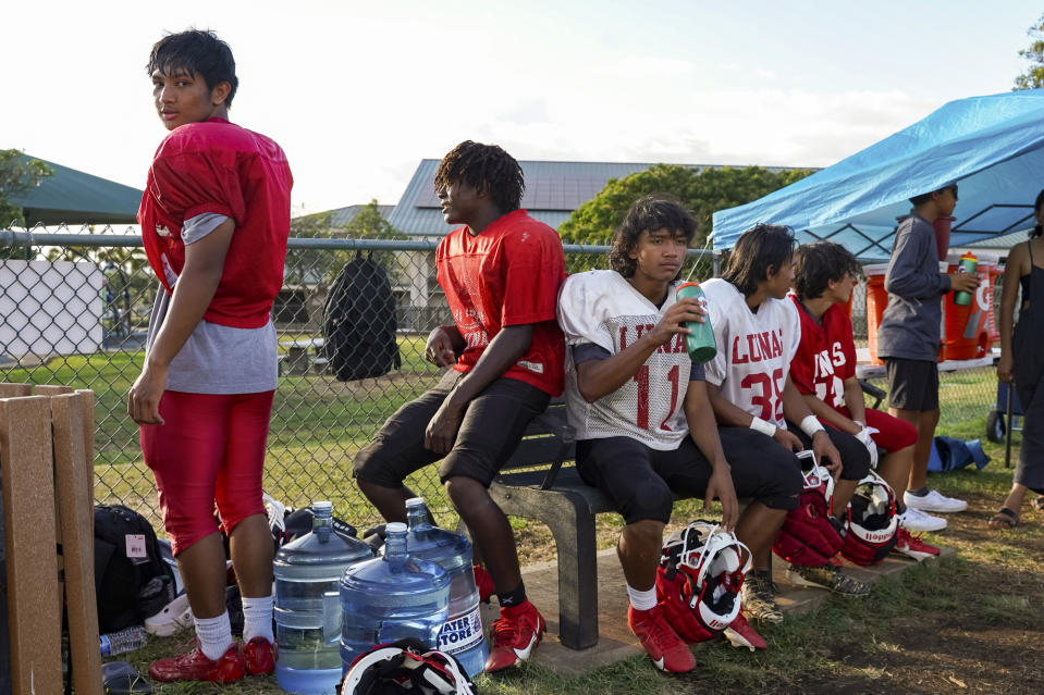 Lahainaluna High School football team players take a break during a practice at Kihei Community Park, Tuesday, Oct. 3, 2023, in Lahaina, Hawaii. Lahainaluna’s varsity and junior varsity football teams are getting back to normal since the devastating wildfire in August. (AP Photo/Mengshin Lin)