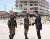 FILE - This Aug. 1, 2013 file photo posted on the official Facebook page of the Syrian Presidency shows Syrian President Bashar Assad shaking hands with a soldier during Syrian Arab Army day in Darya, Syria. As the Syrian conflict entered its forth year this month and large parts of the country are either destroyed or under opposition control, Syrian officials say the presidential elections will be held on time later this year.The opposition rejects such a move saying after the death of more than 140,000 people and millions turned to refugees or displaced, Assad should step down rather than run again. (AP Photo/Syrian Presidency via Facebook, File)