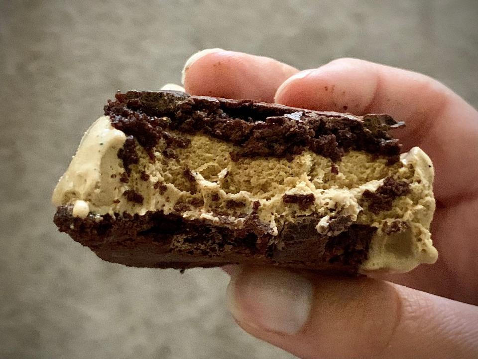 hand holding bitten into brownie crisp ice cream sandwich from trader joe's