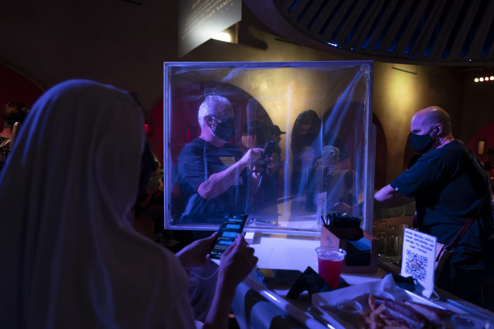 FILE - In this Tuesday, May 4, 2021, file photo, customers look at their smartphones while drinking at Scum and Villainy Cantina, a bar located on Hollywood Blvd, in Los Angeles. California has the lowest infection rate in the country. Los Angeles County, which is home to a quarter of the state's nearly 40 million people and has endured a disproportionate number of the state's 60,000 deaths, didn't record a single COVID-19 death Sunday or Monday, which was likely due to incomplete weekend reporting but still noteworthy. Business and agricultural groups are renewing their criticism of new rules adopted by California Gov. Gavin Newsom's workplace regulators. But there is little chance they can quickly change them unless Newsom steps in, which he seemed disinclined to do Friday, June 4. (AP Photo/Jae C. Hong, File)