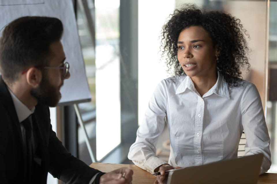 Multiracial business partners met in office sit at desk negotiating focus on american businesslady talking to client make profitable proposition, job interview process HR manager and applicant concept