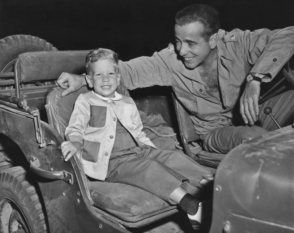 <p>Humphrey Bogart smiles as his and Lauren Bacall's son, Stephen Bogart, visits the set of his film Battle Circus in 1953. </p>