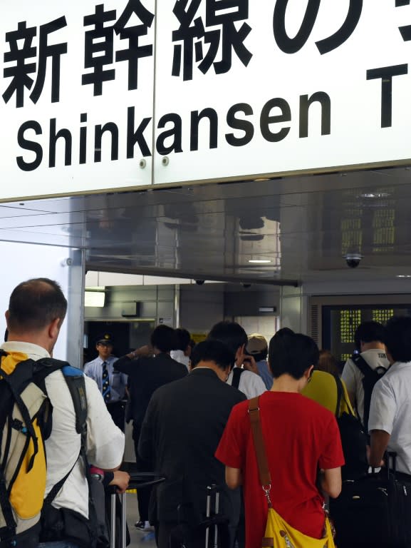 Passengers wait for information outside the shinkansen bullet train ticket barrier at Tokyo station on June 30, 2015 after service was disrupted due to an apparent suicide attempt on board