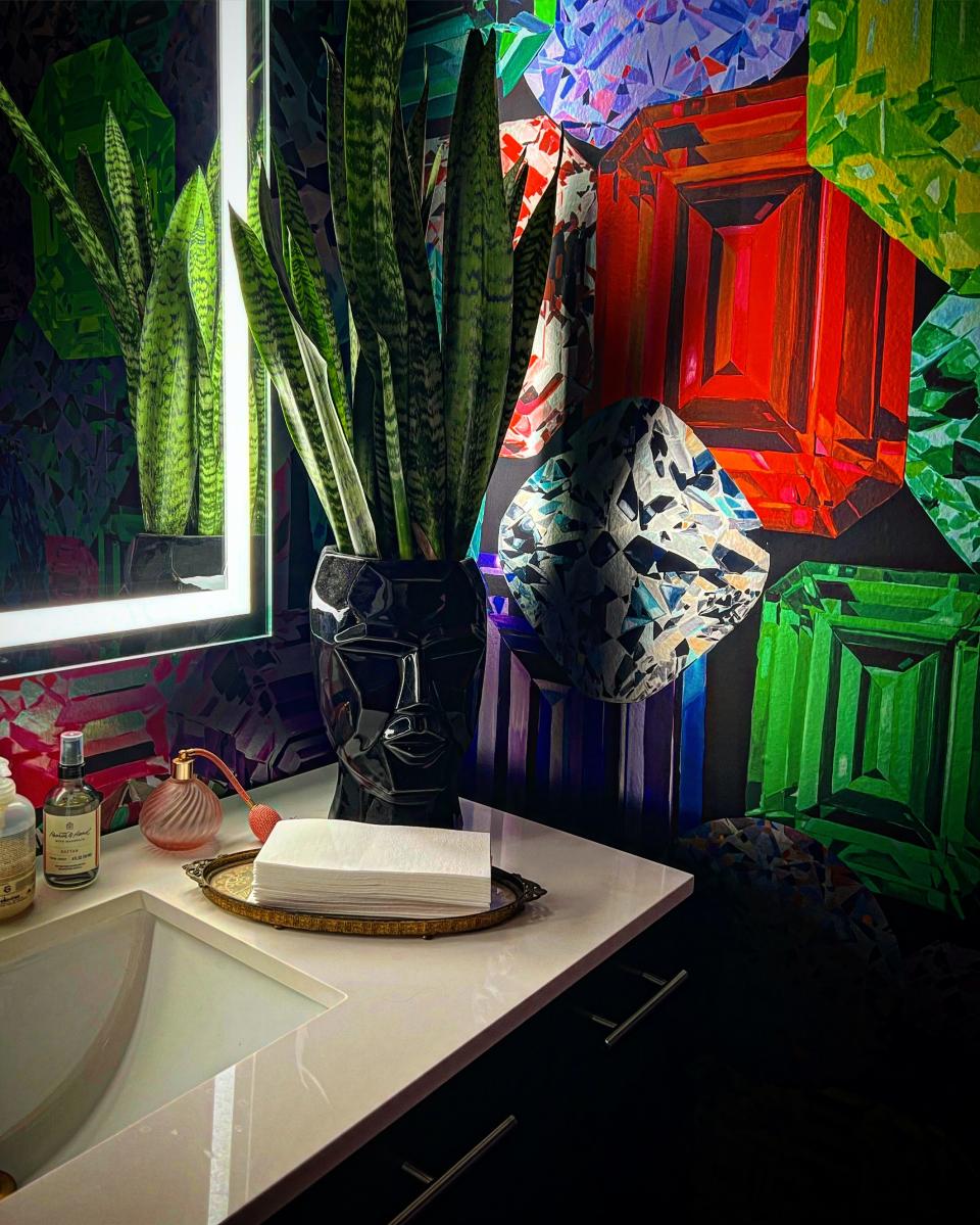 A powder room decorated by designer Daniel Russo with trendy bold-patterned wallpaper with geometric prints.