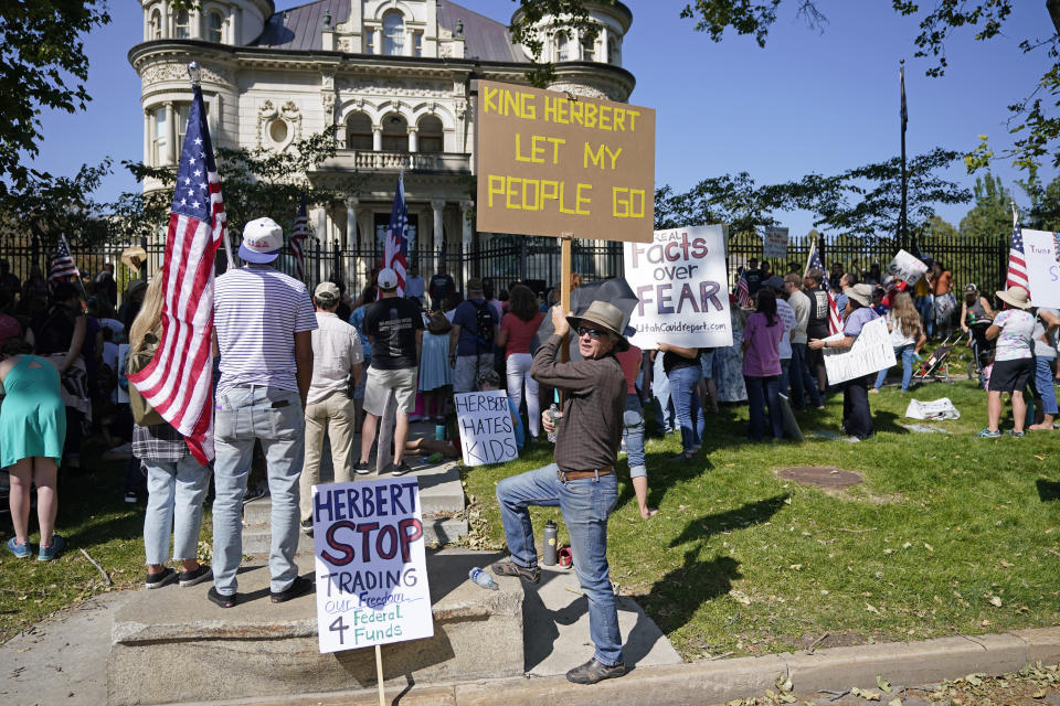 FILE - In this Sept. 12, 2020, file photo, people protest Gov. Gary Herbert during an anti-mask rally outside of the Governors Mansion in Salt Lake City. Virus cases are surging across Europe and many U.S. states, but responses by leaders are miles apart, with officials in Ireland, France and elsewhere imposing curfews and restricting gatherings even as some U.S. governors resist mask mandates or more aggressive measures. Herbert, who has been pressured by an outspoken contingent of residents opposed to masks, has resisted a statewide mandate. (AP Photo/Rick Bowmer, File)