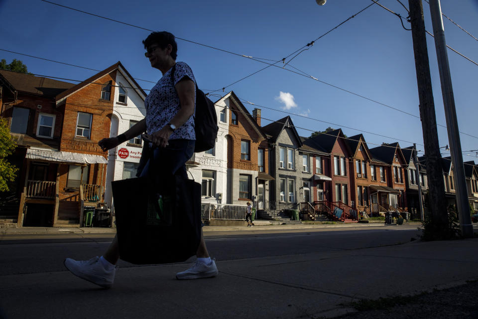 A person walks by a row of houses in Toronto on Tuesday July 12, 2022. Realtors are expecting a spring shift in a housing market that has been sluggish since last year, when prospective buyers started putting off plans to purchase homes as the Bank of Canada aggressively hiked interest rates eight times. THE CANADIAN PRESS/Cole Burston