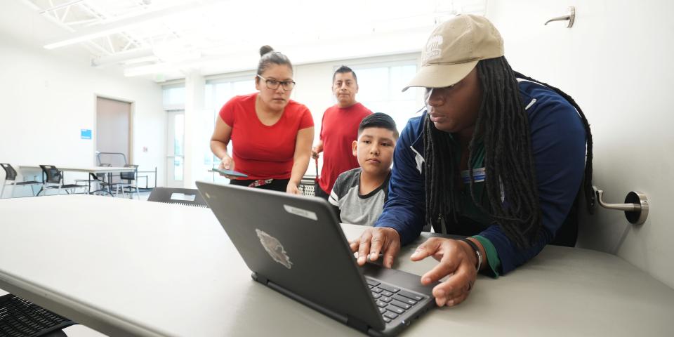 As the Columbus City Schools teacher strike moves into the third day, Columbus Recreation and Parks staffer Ambrosia Lamarr helps Asher Aquino, 11, login at the Linden Community Center. Behind Asher are his parents, Antonio Bargas and Graciela Aquino.