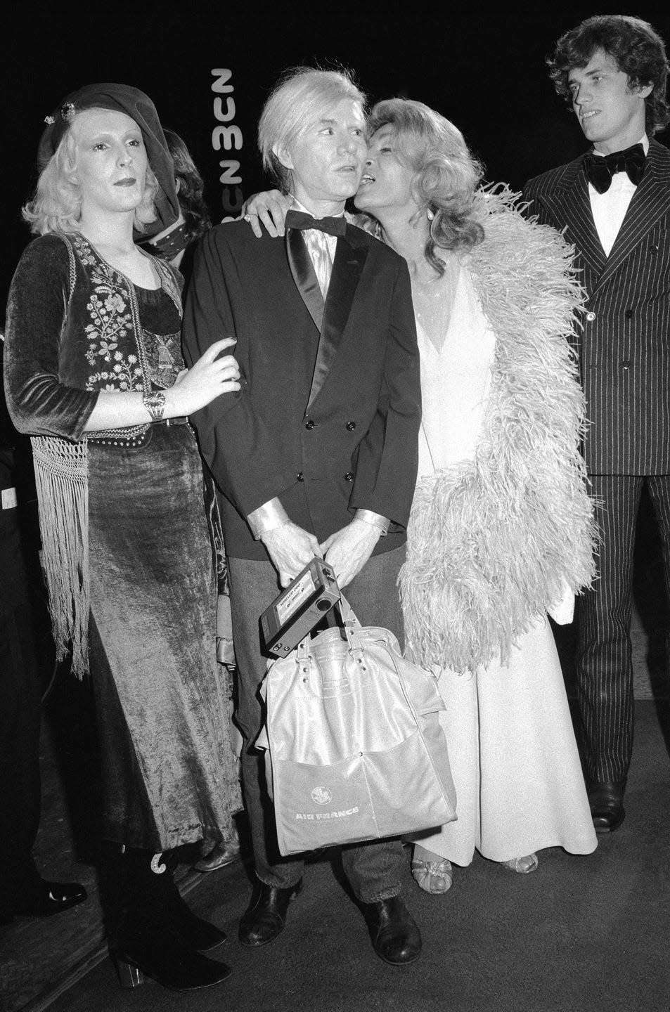 <p>Warhol seems confused by actress Sylvia Miles's intimate interaction with him, as he arrives to the Fiddler on the Roof premiere at the Rivoli Theater, along with Candy Darling.</p>