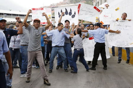 Empresas Polar workers hold placards and shout in a facility used by the company as a distribution center, during the occupation of its installations by government representatives in Caracas July 30, 2015. REUTERS/Carlos Garcia Rawlins