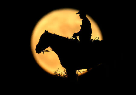 A full moon rises behind U.S. Border Patrol agent Josh Gehrich as he sits atop a hill while on patrol near Jacumba, California, U.S., November 14, 2016. REUTERS/Mike Blake