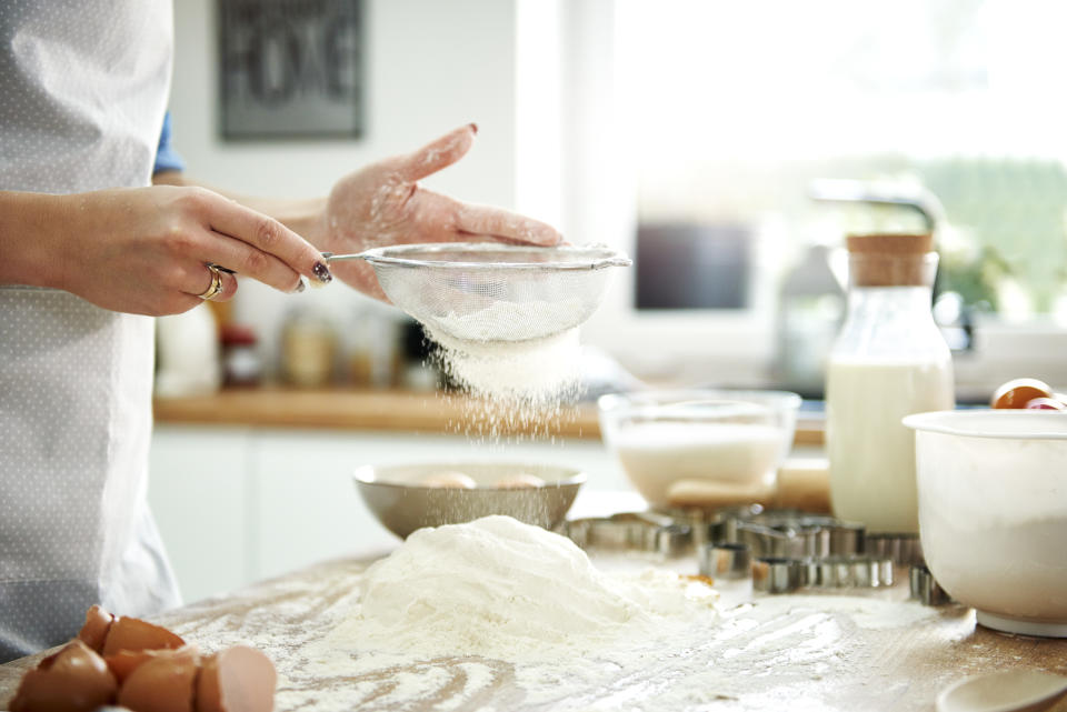 Woman sifting flour in kitchen