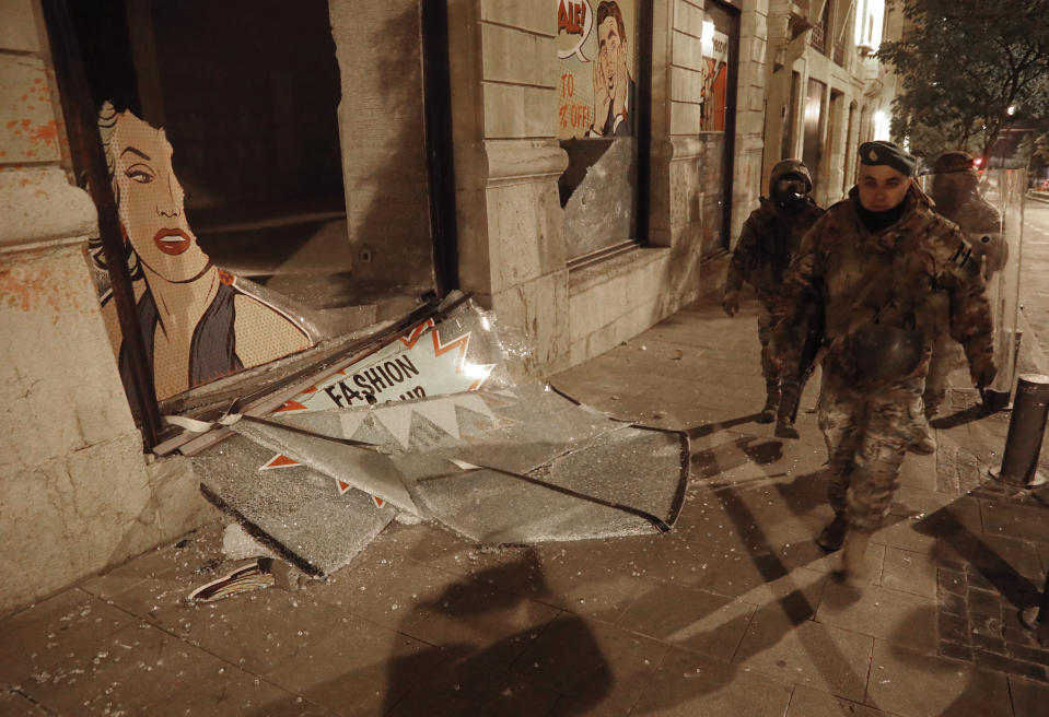 Lebanese army soldiers pass next of windows shop that smashed by anti-government protesters, during a protest against the new government, in downtown Beirut, Lebanon, Wednesday, Jan. 22, 2020. Lebanon's new government, made up of members nominated by the Shiite group Hezbollah and its allies got down to business Wednesday, a day after it was formed. Questions arose immediately about its ability to halt a spiral of economic and political collapse. (AP Photo/Hussein Malla)