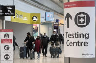 Passengers arrive at Heathrow Airport in London, Monday, Nov. 29, 2021. The new potentially more contagious omicron variant of the coronavirus popped up in more European countries on Saturday, just days after being identified in South Africa, leaving governments around the world scrambling to stop the spread. In Britain, Prime Minister Boris Johnson said mask-wearing in shops and on public transport will be required, starting Tuesday. (AP Photo/Frank Augstein)