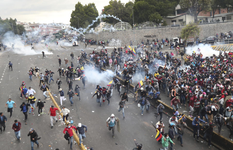 Manifestantes antigubernamentales corren a guarecerse mientras las fuerzas de seguridad arrojan gases lacrimógenos para dispersarlos cerca de la Asamblea Nacional, en Quito, Ecuador, el viernes 11 de octubre de 2019. (AP Foto/Dolores Ochoa)