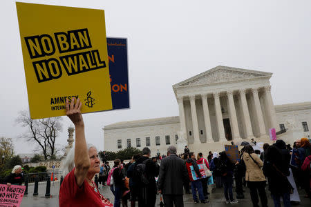 A protester holds a placard outside the U.S. Supreme Court, while the court justices consider case regarding presidential powers as it weighs the legality of President Donald Trump's latest travel ban targeting people from Muslim-majority countries, in Washington, DC, U.S., April 25, 2018. REUTERS/Yuri Gripas