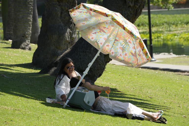 Las personas disfrutan de refrescos a la sombra en el Echo Park Lake en Los Ángeles el miércoles 5 de julio de 2023. 