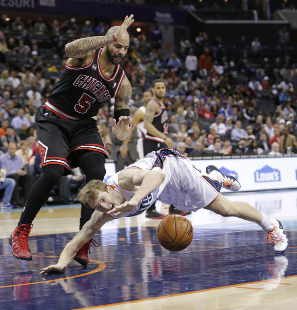 Charlotte Bobcats' Cody Zeller, front, loses the ball as he falls in front of Chicago Bulls' Carlos Boozer during the first half of an NBA basketball game in Charlotte, N.C., Wednesday, April 16, 2014. (AP Photo/Chuck Burton)
