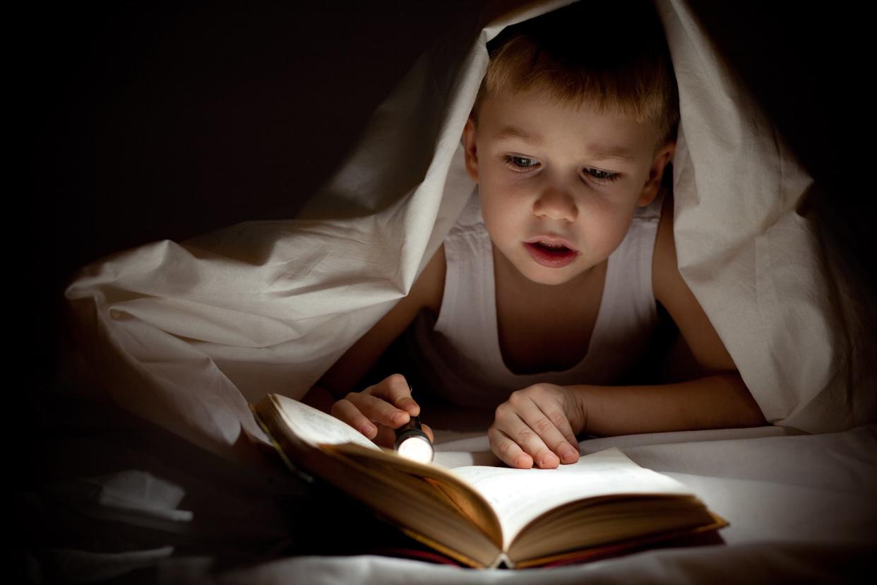 boy reading book in bed