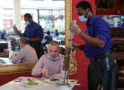 A worker wearing a protective face mask and gloves serves food at a restaurant during the reopening of malls, following the outbreak of the coronavirus disease (COVID-19), at Mall of the Emirates in Dubai