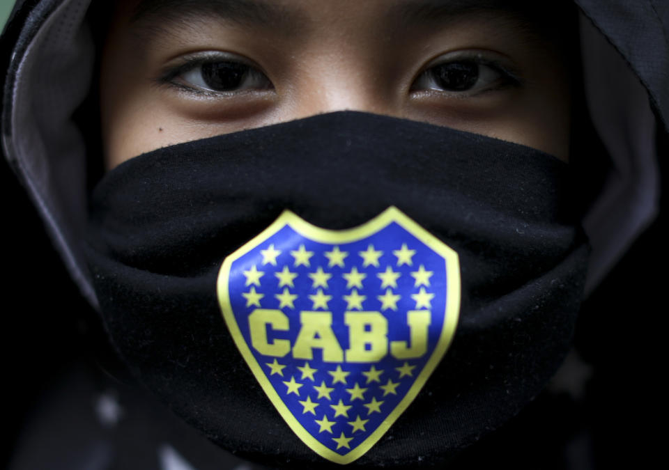 Thiago Laura posa para una foto con una mascarilla de Boca Juniors mientras espera por comida en un comedor comunitario en el barrio de Fraga en Buenos Aires, Argentina, el sábado 6 de junio de 2020. (AP Foto/Natacha Pisarenko)