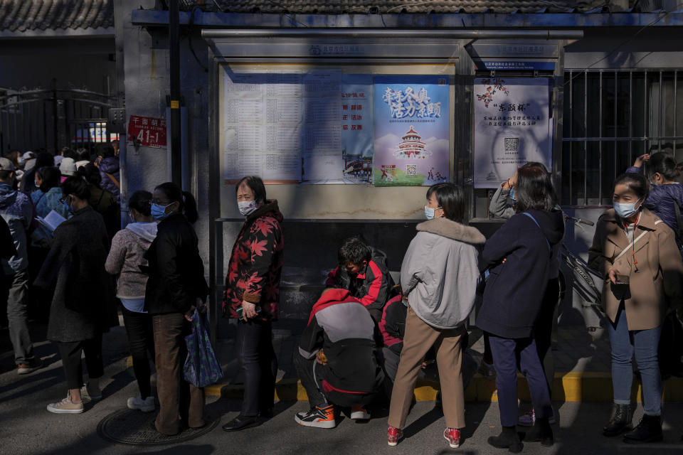 Residents wearing face masks to help curb the spread of the coronavirus line up to receive booster shots against COVID-19 at a vaccination site with a billboard displaying a propaganda poster supporting the Beijing 2022 Winter Olympic Games, near a residential area in Beijing, Friday, Oct. 22, 2021. China's capital Beijing has begun offering booster shots against COVID-19, four months before the city and surrounding regions are to host the Winter Olympics. (AP Photo/Andy Wong)