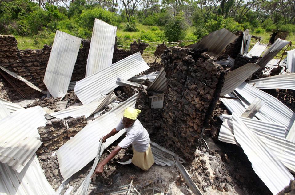 A resident rummages through the ruins of her building burnt down after gunmen attacked Hindi village, near Lamu