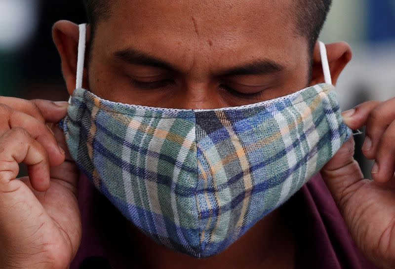 FILE PHOTO: A migrant worker puts on a mask at a dormitory, amid the coronavirus disease (COVID-19) outbreak in Singapore