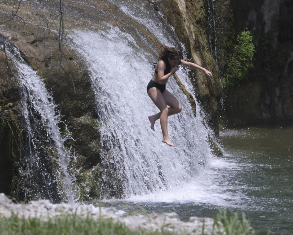 A young girl jumps off the natural waterfall at Tonkawa Falls, Friday, June 16, 2023 near Crawford, Texas. Temperatures are expected to reach the 100 degree Fahrenheit mark for the next several days. (Rod Aydelotte/Waco Tribune-Herald via AP)