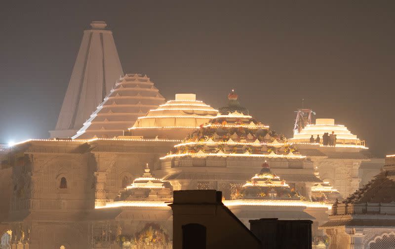 Labourers stand on top of the illuminated grand temple of Lord Ram ahead of its opening in Ayodhya