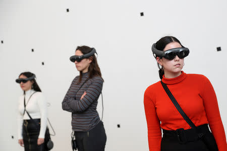 Attendees look through augmented reality glasses at Marina Abramovic's exhibition 'The Life', the world's first large-scale performance exhibited using Mixed Reality at the Serpentine Gallery in London, Britain February 18, 2019. REUTERS/Simon Dawson