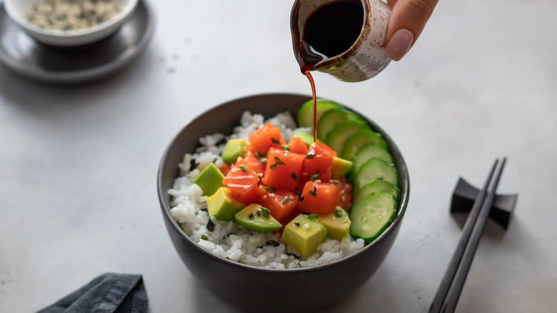 Pouring soy sauce into poke bowl