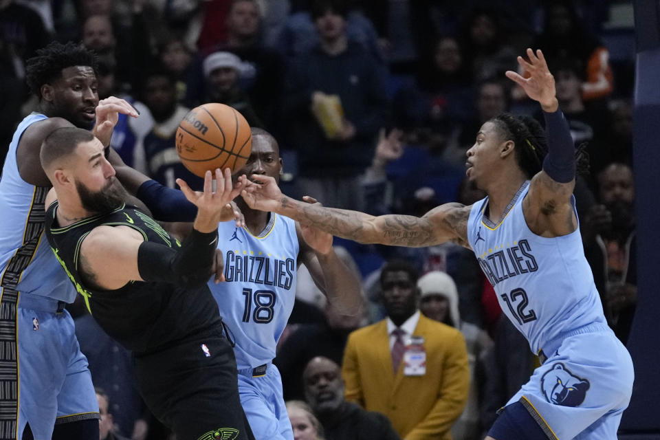 New Orleans Pelicans center Jonas Valanciunas (17) battles near the basket with Memphis Grizzlies guard Ja Morant (12) in the first half of an NBA basketball game in New Orleans, Tuesday, Dec. 26, 2023. (AP Photo/Gerald Herbert)