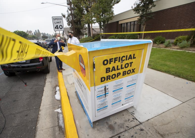 BALDWIN PARK, CA - OCTOBER 19: Manuel Lozano, left, Baldwin Park mayor, and Sam Gutierrez, director of public works, view the fire damage to the official ballot drop box where ballots were set on fire outside the Baldwin Park Library in Baldwin Park Monday, Oct. 19, 2020. Authorities are investigating a fire which damaged an official ballot drop box Sunday night in Baldwin Park, damaging countless ballots in the process. The box was discovered on fire at around 8 p.m., according to Baldwin Park police. (Allen J. Schaben / Los Angeles Times)